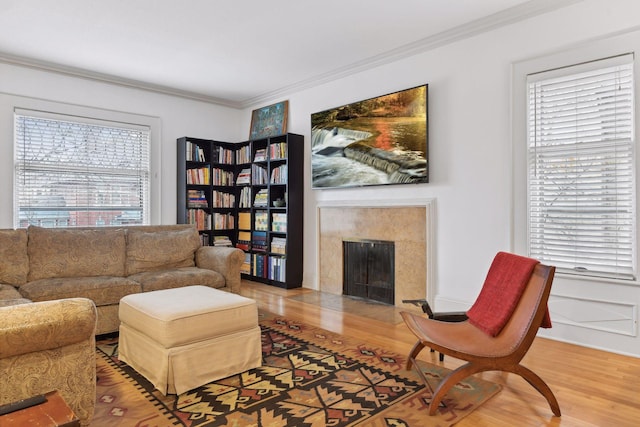 living room with a high end fireplace, hardwood / wood-style floors, crown molding, and a healthy amount of sunlight