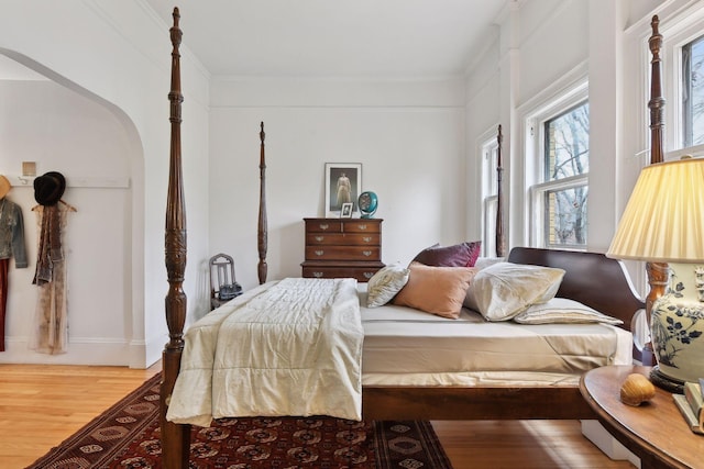 bedroom with multiple windows, crown molding, and hardwood / wood-style flooring