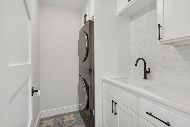 laundry room with sink, cabinets, and stacked washer and clothes dryer