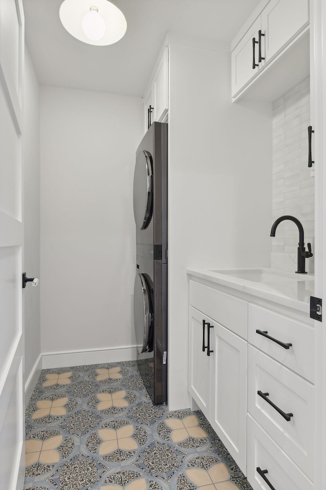 laundry room featuring sink, light tile patterned floors, cabinets, and stacked washer and clothes dryer