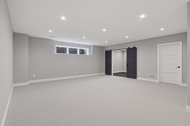 basement with a barn door and light carpet