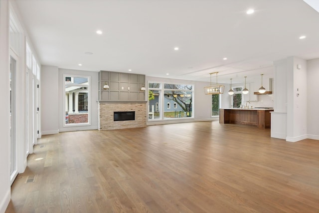 unfurnished living room with a fireplace, light hardwood / wood-style flooring, and sink