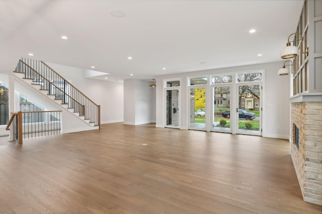 unfurnished living room with a healthy amount of sunlight, light wood-type flooring, and a fireplace