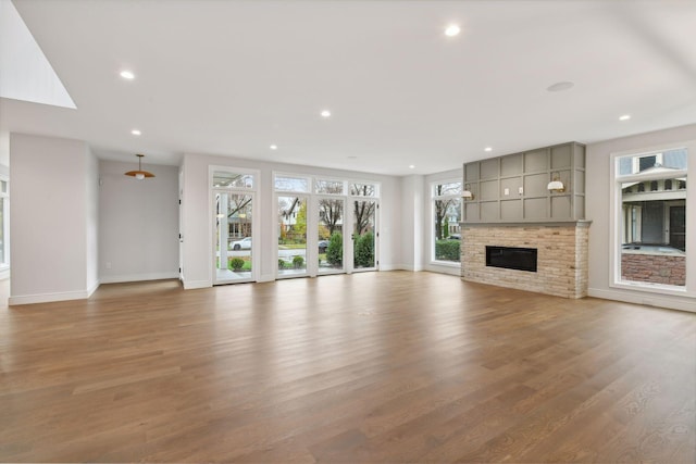 unfurnished living room featuring hardwood / wood-style flooring, a fireplace, and a wealth of natural light