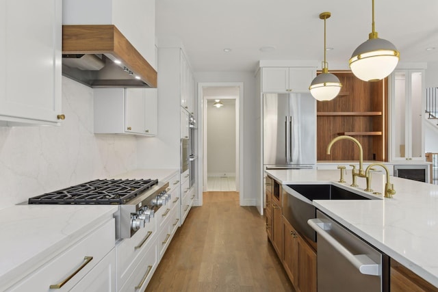 kitchen with light stone countertops, custom range hood, stainless steel appliances, wood-type flooring, and white cabinets