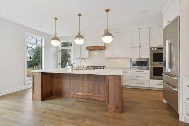 kitchen featuring white cabinetry, sink, hardwood / wood-style floors, a kitchen island with sink, and appliances with stainless steel finishes