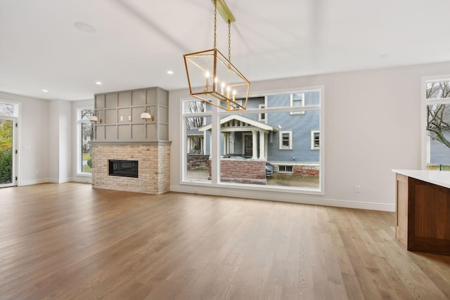 unfurnished living room with a fireplace, light hardwood / wood-style flooring, and a healthy amount of sunlight