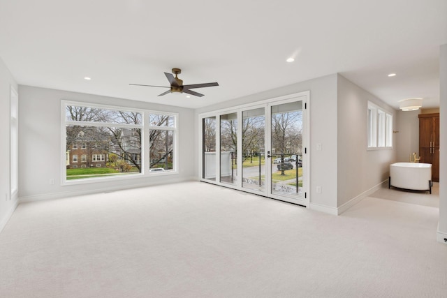 unfurnished living room featuring light carpet, plenty of natural light, and ceiling fan