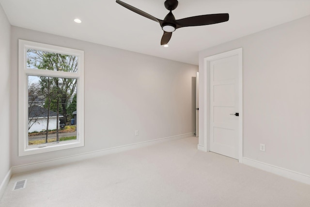 unfurnished room featuring plenty of natural light, ceiling fan, and light colored carpet