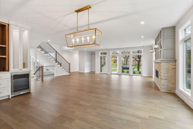 unfurnished living room with hardwood / wood-style flooring, plenty of natural light, and beverage cooler