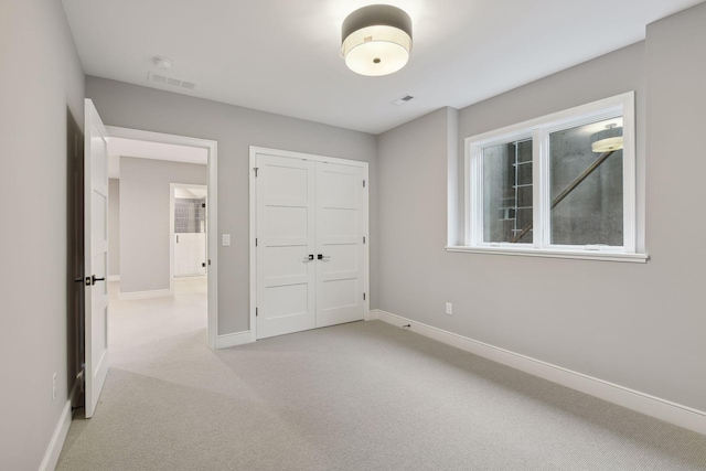 unfurnished bedroom featuring light carpet and a closet