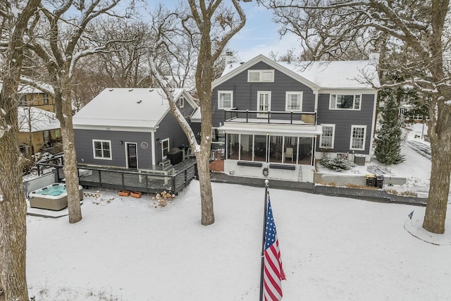 snow covered property with a balcony, a sunroom, and a chimney