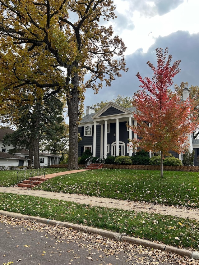 greek revival house featuring a front yard and a chimney