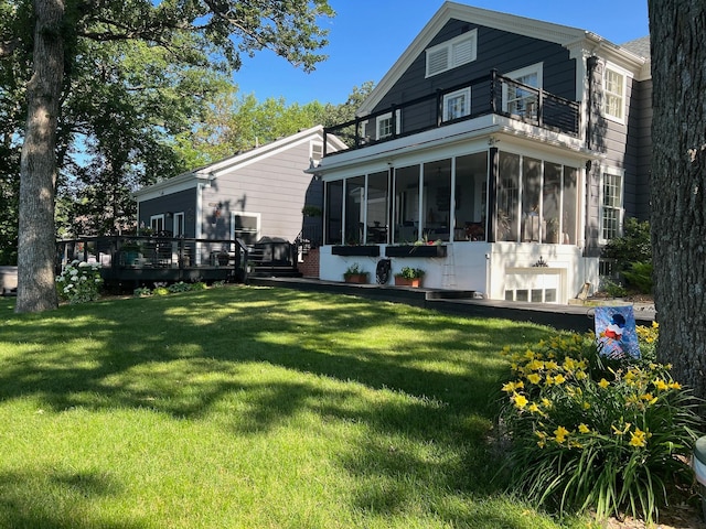 back of house with a lawn, a balcony, and a sunroom