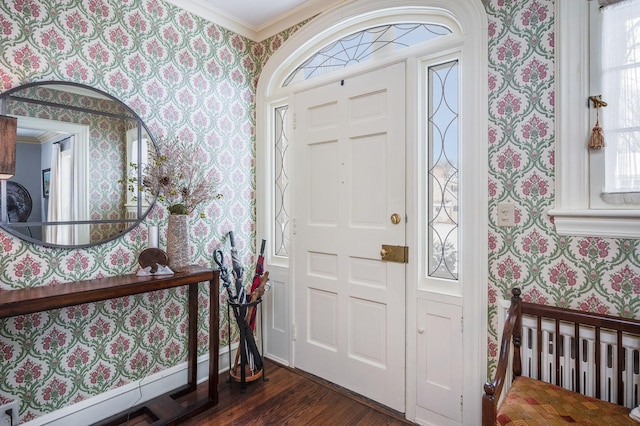 entrance foyer featuring baseboards, wallpapered walls, dark wood-style flooring, ornamental molding, and a wealth of natural light