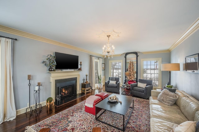 living area featuring crown molding, baseboards, a lit fireplace, an inviting chandelier, and wood finished floors