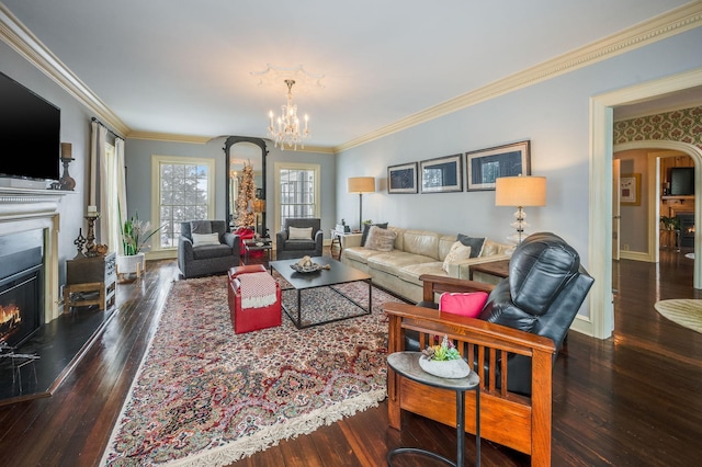 living room featuring ornamental molding, a warm lit fireplace, hardwood / wood-style floors, arched walkways, and a chandelier