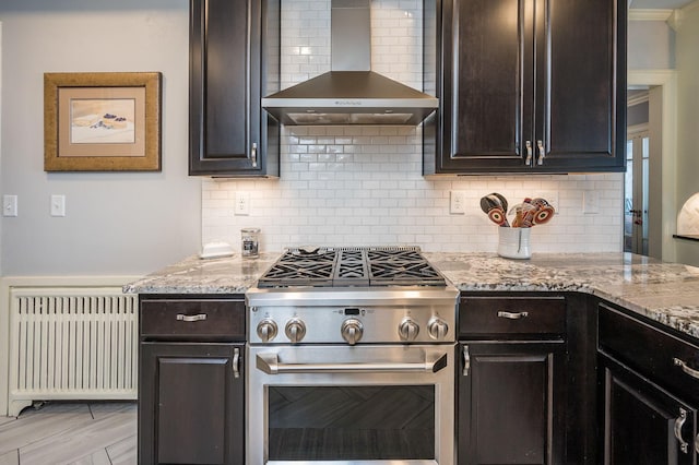 kitchen featuring dark brown cabinets, radiator heating unit, stainless steel range, and wall chimney exhaust hood