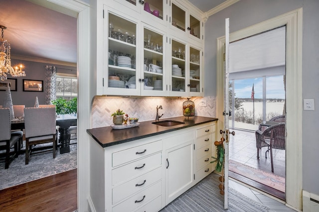 kitchen featuring a sink, tasteful backsplash, dark countertops, and ornamental molding