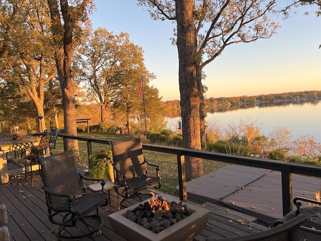 deck at dusk featuring a fire pit and a water view