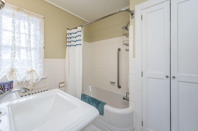 full bathroom featuring wainscoting, shower / bath combination with curtain, tile walls, and a sink