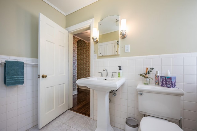 bathroom featuring a wainscoted wall, ornamental molding, tile patterned flooring, tile walls, and toilet