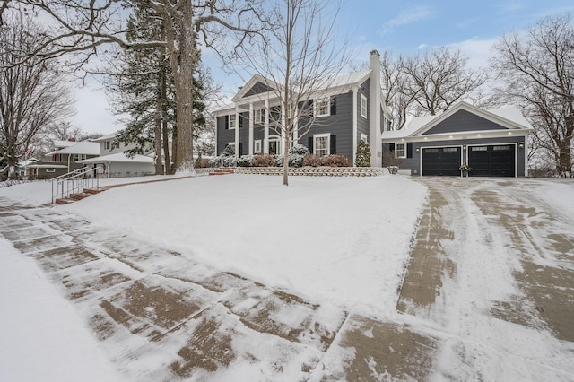 view of front of home featuring a garage, a chimney, and driveway