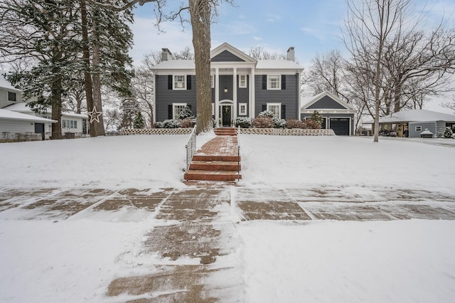 neoclassical home featuring an attached garage and a chimney