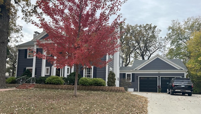 view of front facade with a chimney, concrete driveway, and a garage