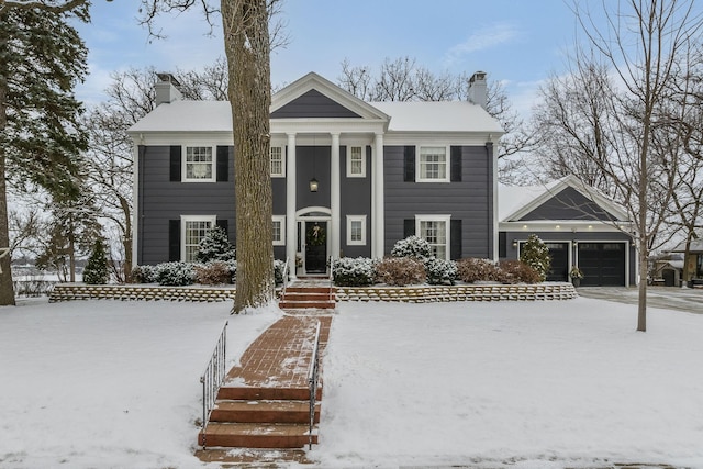 greek revival inspired property with a garage and a chimney