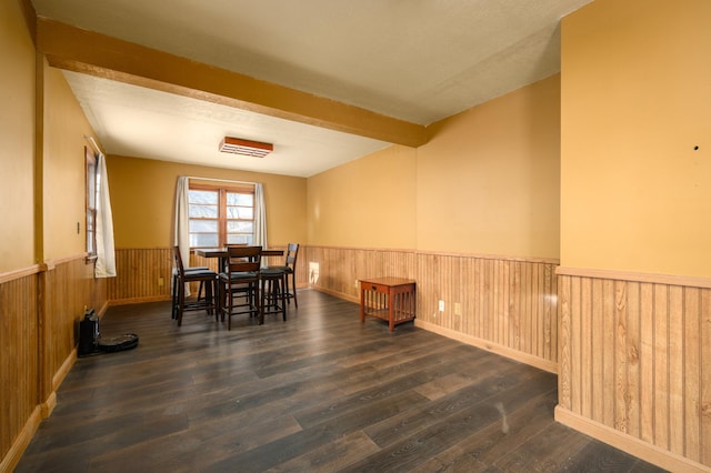 dining area with beamed ceiling, dark wood-type flooring, and wood walls