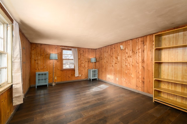 unfurnished living room with dark wood-type flooring and wood walls