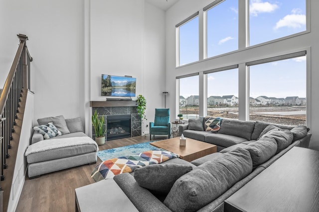 living room with hardwood / wood-style floors, a high ceiling, a wealth of natural light, and a tiled fireplace