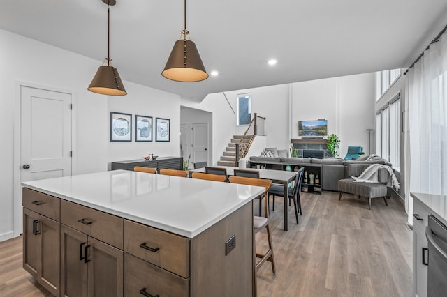 kitchen featuring a stone fireplace, plenty of natural light, pendant lighting, light hardwood / wood-style floors, and a kitchen island