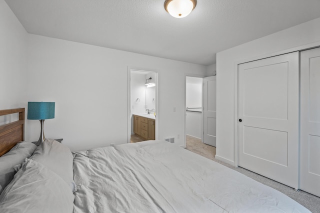 bedroom with light carpet, ensuite bath, a closet, and sink