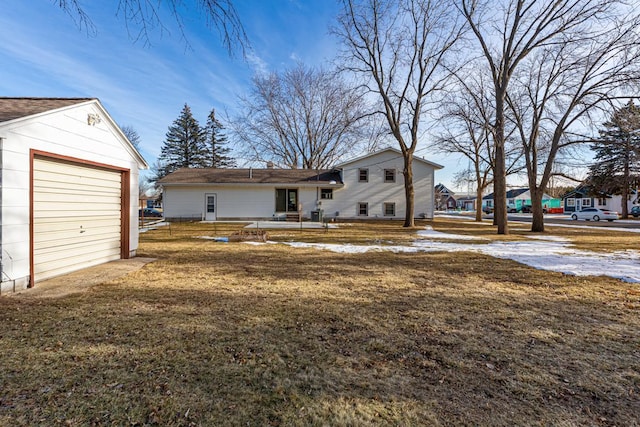 back of property featuring a garage and a lawn