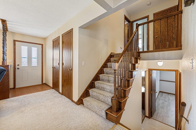 foyer entrance featuring light carpet and a textured ceiling