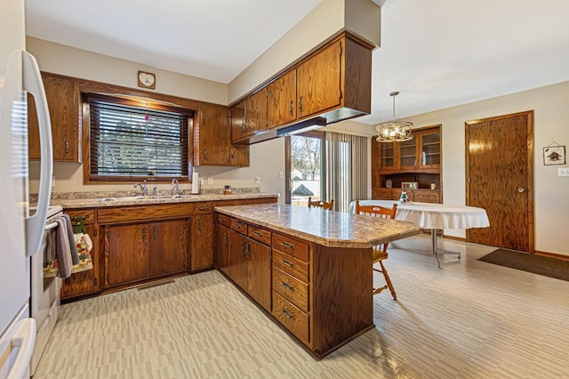 kitchen with kitchen peninsula, decorative light fixtures, a wealth of natural light, and white fridge