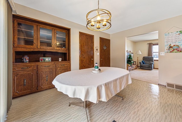 dining area featuring light colored carpet and a notable chandelier