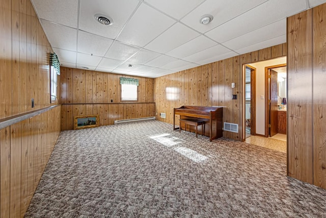 interior space featuring carpet, a drop ceiling, and a baseboard heating unit