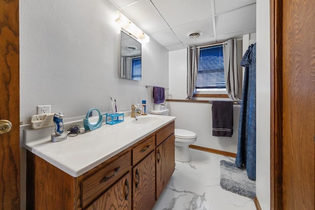 bathroom with vanity, toilet, and a drop ceiling