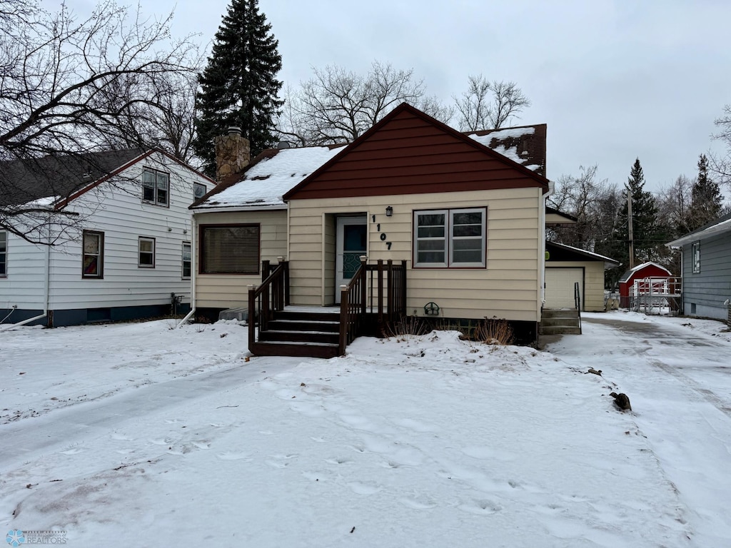 view of front of home featuring a garage and an outbuilding