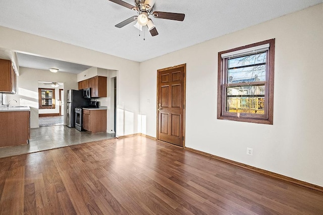 unfurnished living room with ceiling fan, sink, and light hardwood / wood-style flooring