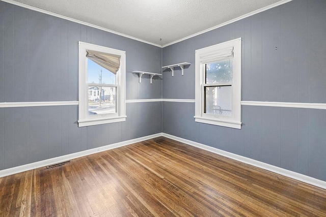 spare room with hardwood / wood-style flooring, a wealth of natural light, and ornamental molding