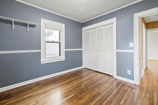 unfurnished bedroom featuring dark hardwood / wood-style flooring, crown molding, a closet, and a textured ceiling