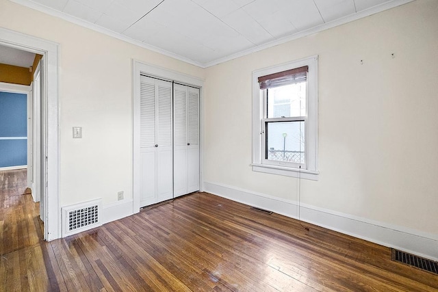 unfurnished bedroom with hardwood / wood-style floors, ornamental molding, and a closet