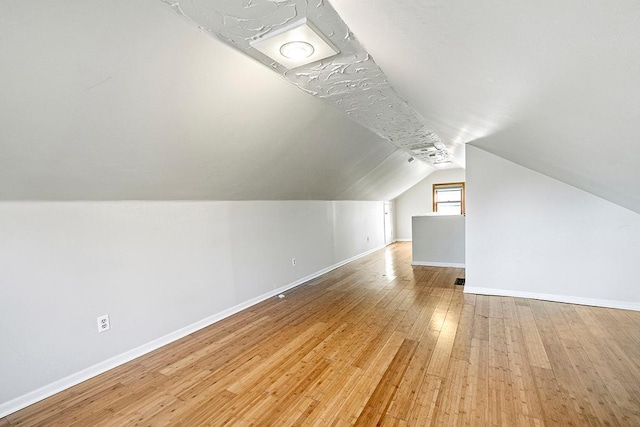 additional living space featuring light hardwood / wood-style floors and lofted ceiling