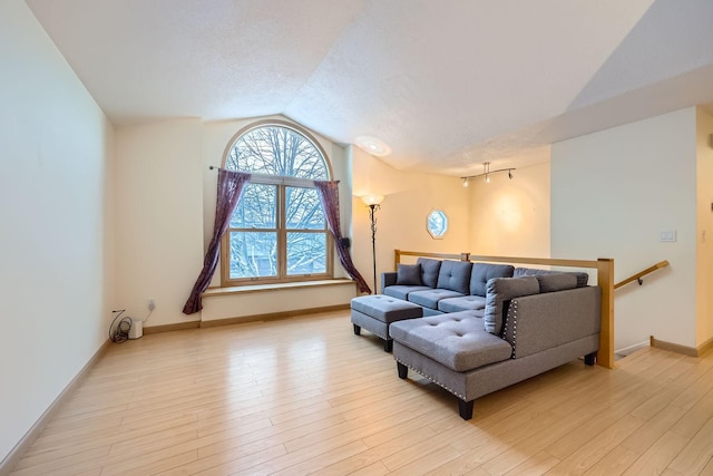 living room featuring lofted ceiling, a textured ceiling, and light hardwood / wood-style flooring