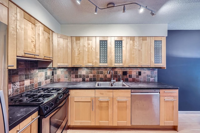 kitchen with sink, light brown cabinets, light hardwood / wood-style floors, decorative backsplash, and appliances with stainless steel finishes