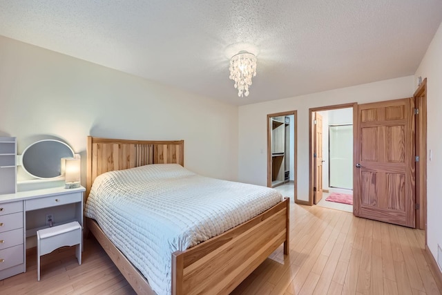 bedroom with ensuite bathroom, light hardwood / wood-style floors, and a textured ceiling